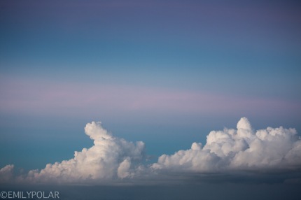 Big puffy white clouds in the blue and pink skies at sunset in Bali.