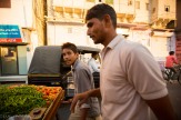 Indian men pushing street cart with vegetables at sunset in Udaipur.